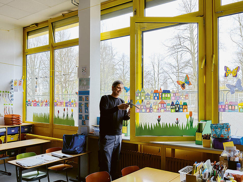 Innenaufnahme: Mann repariert Fenstergriff in Klassenzimmer