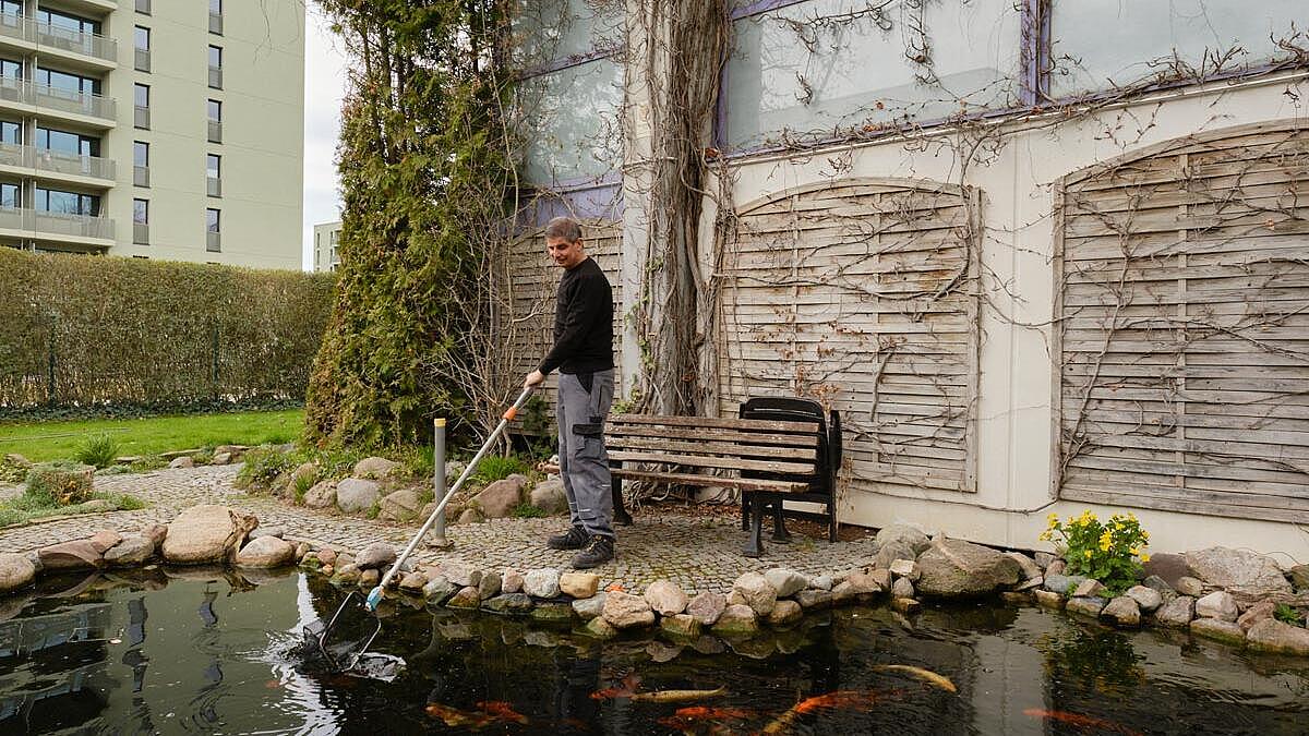 Außenaufnahme: Mann mit Kescher am Fischteich