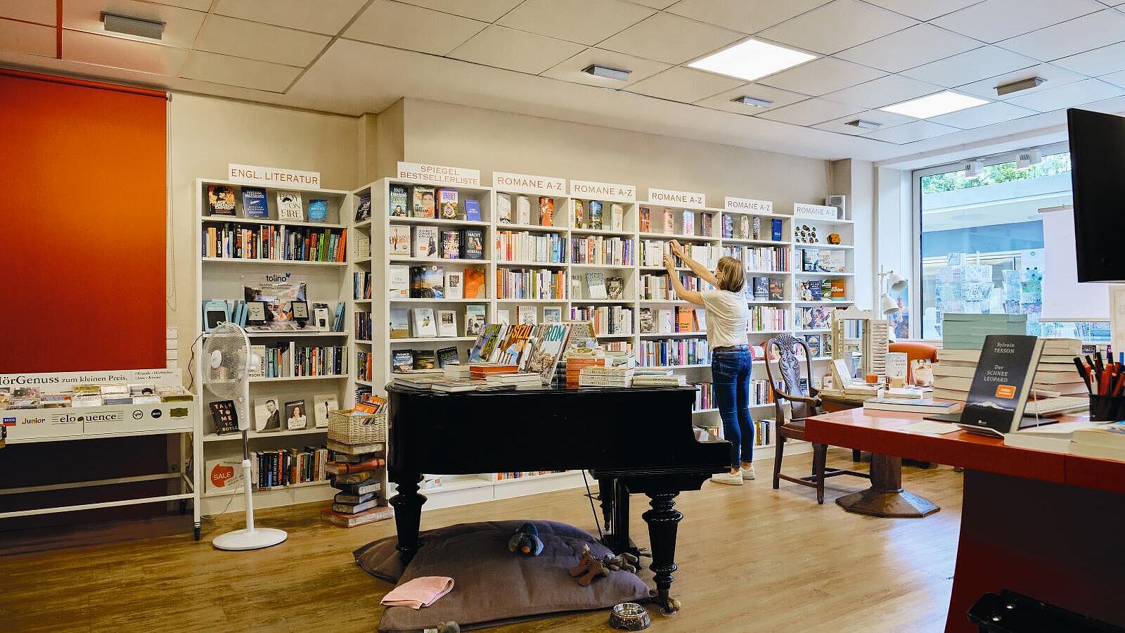 Innenaufnahme: Buchhandlung mit Bücherregalen, im Vordergrund ein Piano