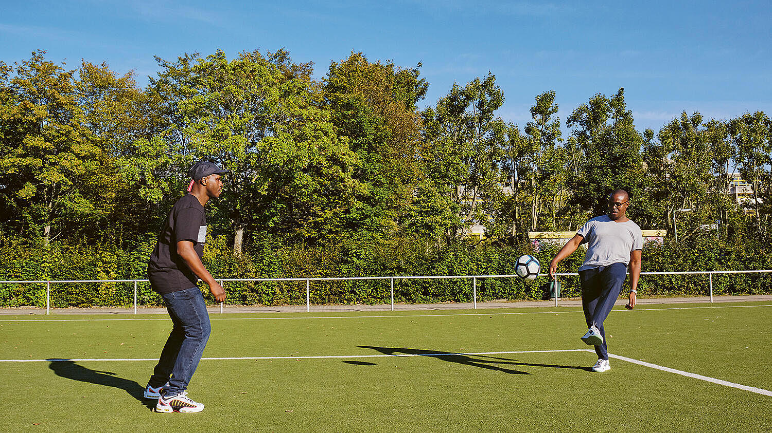 Außenaufnahme: Zwei Männer spielen Fußball auf einem Rasenplatz